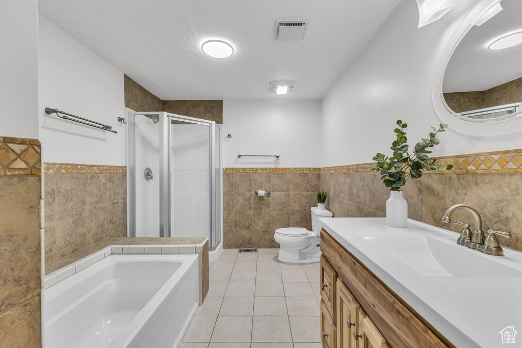 Full bathroom with tile walls, wainscoting, a shower stall, tile patterned floors, and toilet