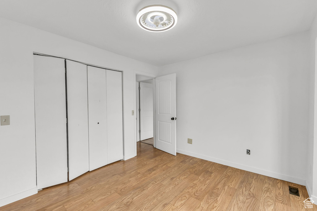Unfurnished bedroom featuring baseboards, light wood-type flooring, and a closet
