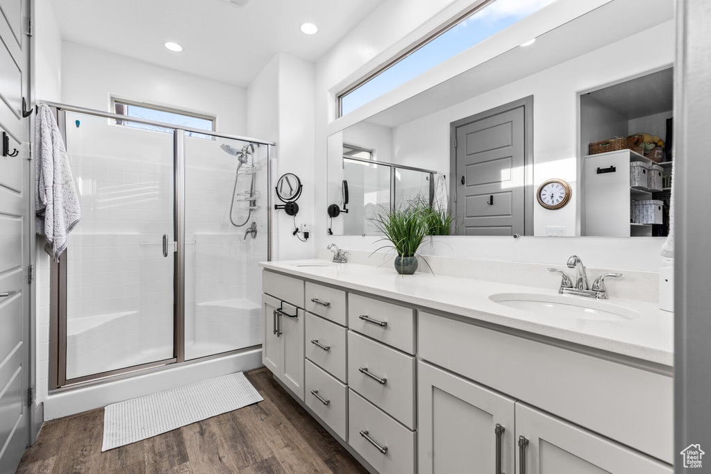Bathroom with a shower stall, wood finished floors, double vanity, and recessed lighting