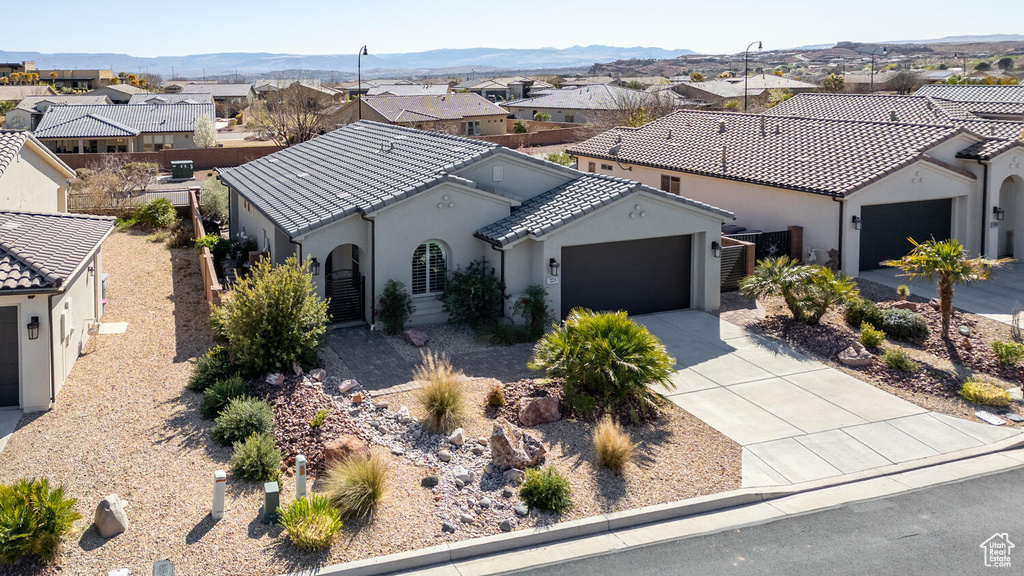 Mediterranean / spanish house with a residential view, stucco siding, a garage, and driveway