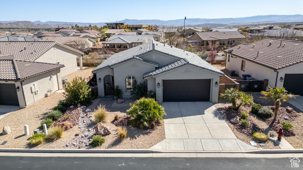 View of front facade featuring a residential view, an attached garage, driveway, and a mountain view