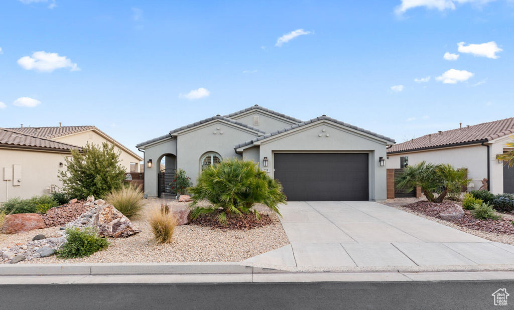 View of front facade featuring a garage, stucco siding, driveway, and a tile roof