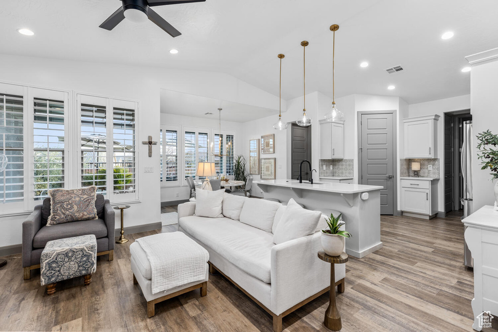 Living area with light wood-type flooring, vaulted ceiling, a ceiling fan, recessed lighting, and baseboards