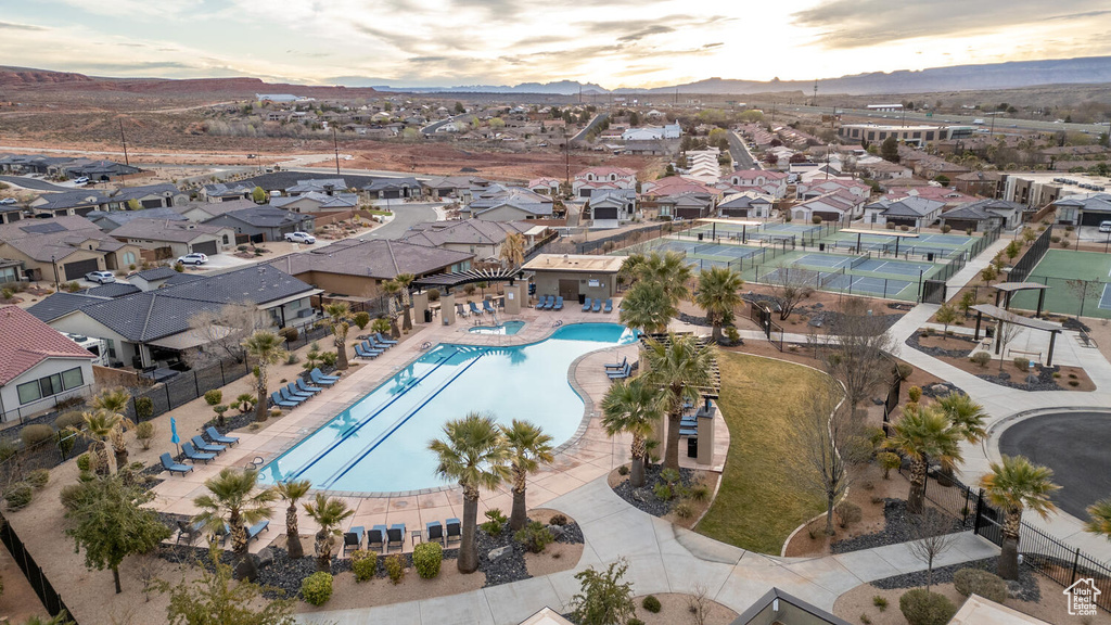Aerial view of property and surrounding area with a pool, a mountainous background, and nearby suburban area