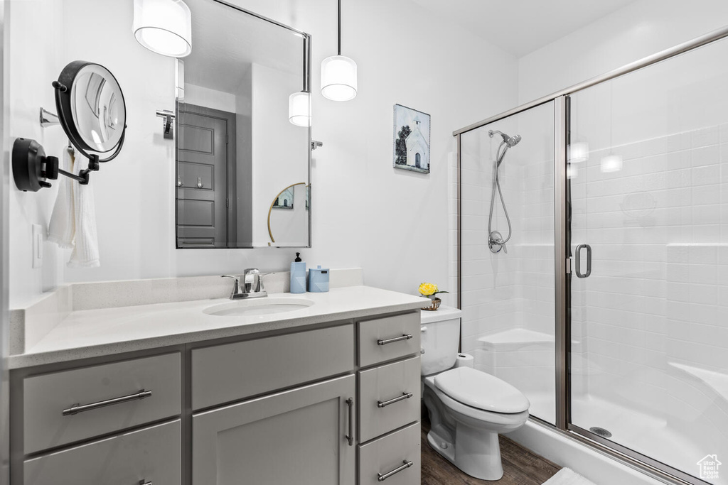 Full bathroom featuring a shower stall, vanity, and wood finished floors