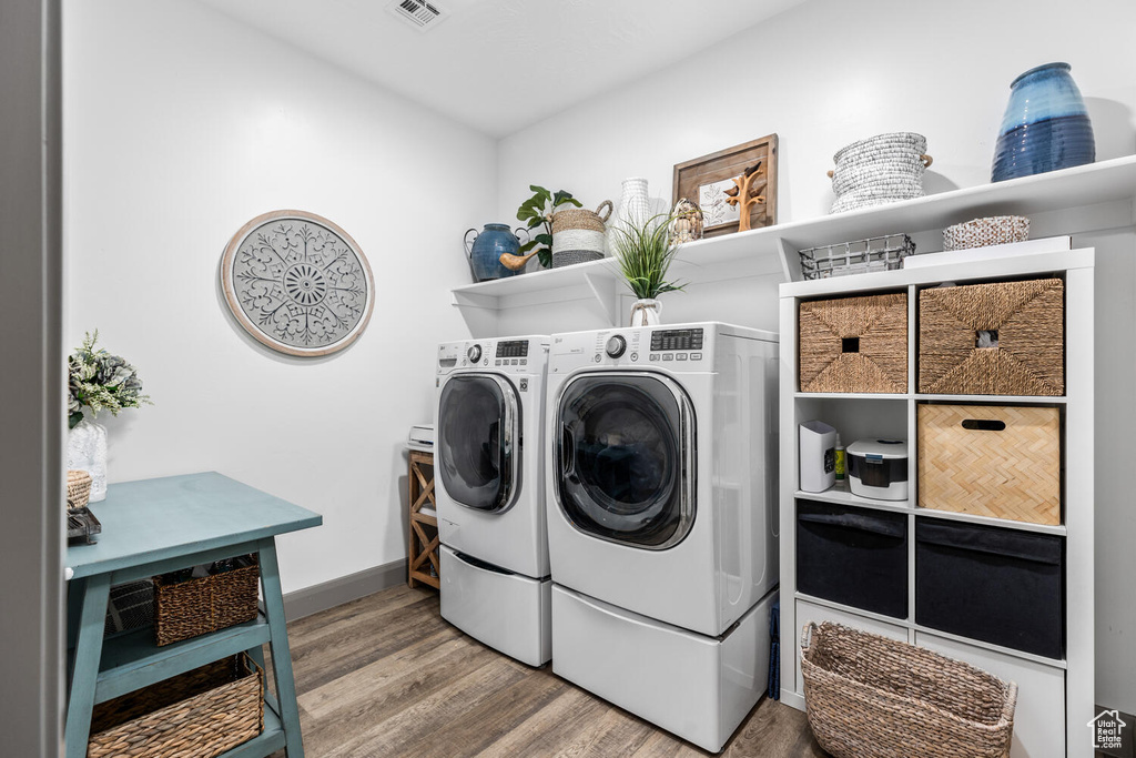 Washroom with wood finished floors, washing machine and dryer, and baseboards