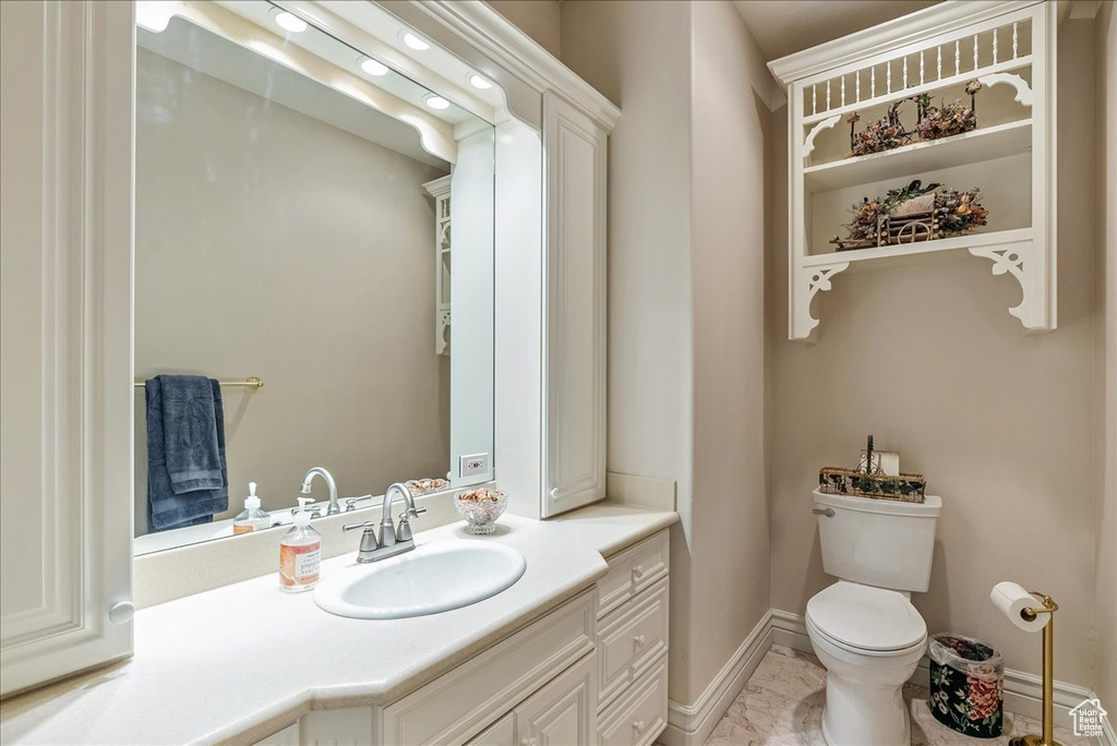 Bathroom with baseboards, vanity, toilet, and marble finish floor