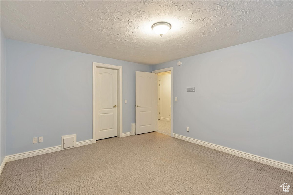Spare room featuring baseboards, light carpet, and a textured ceiling