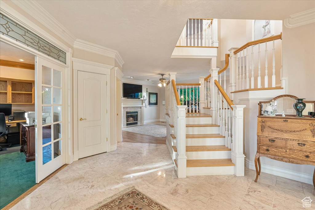 Stairway with ceiling fan, a fireplace, baseboards, marble finish floor, and ornamental molding