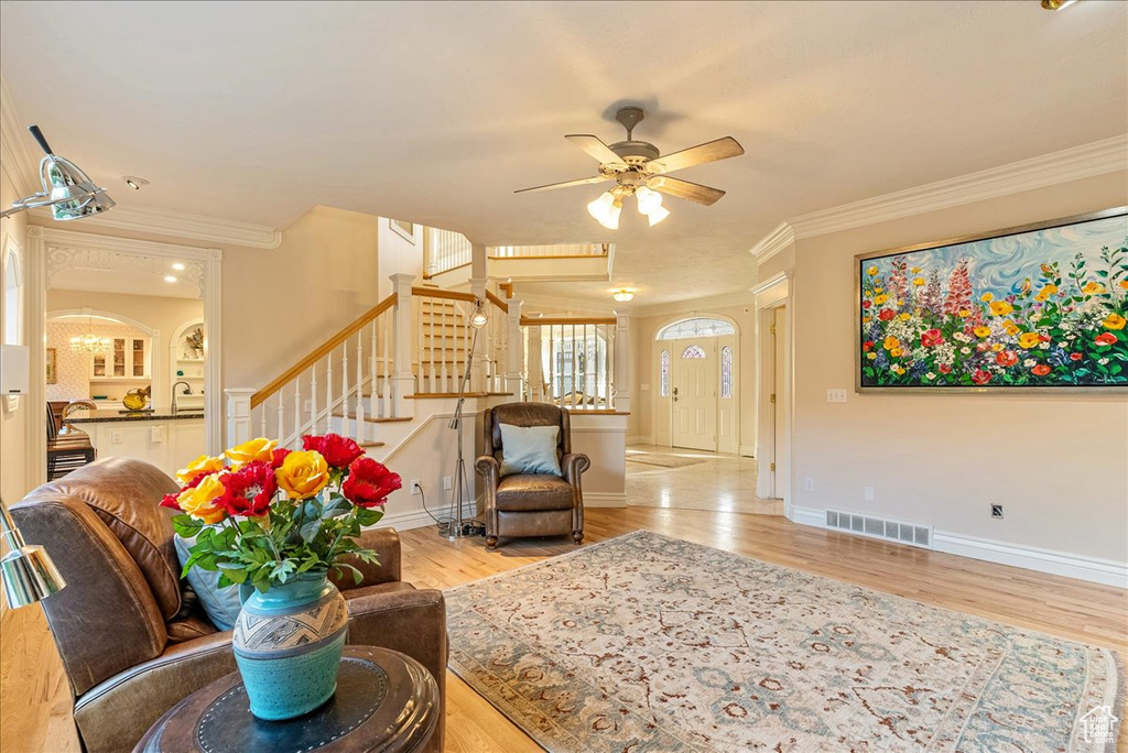 Living room with crown molding, stairs, wood finished floors, and visible vents