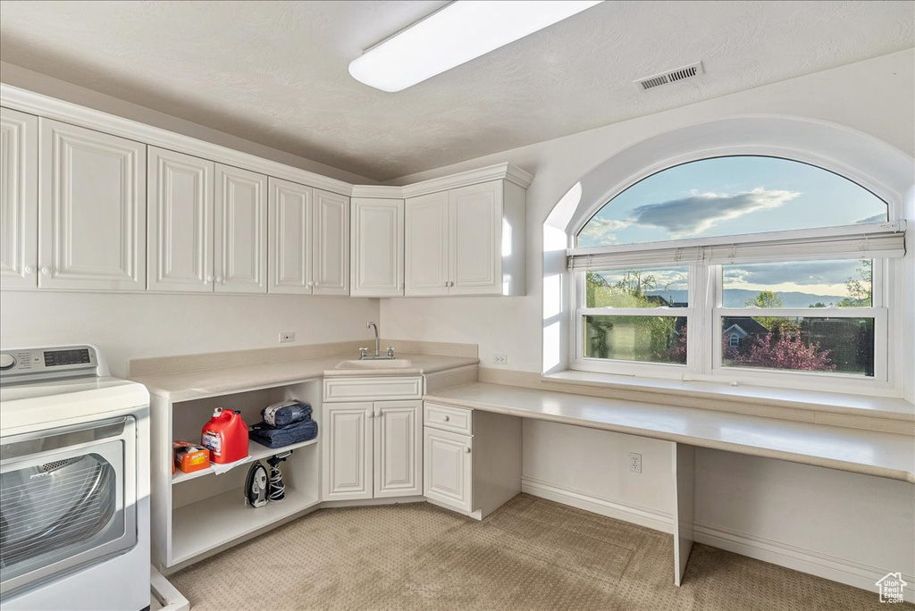 Laundry area with plenty of natural light, visible vents, light colored carpet, a sink, and washer / dryer