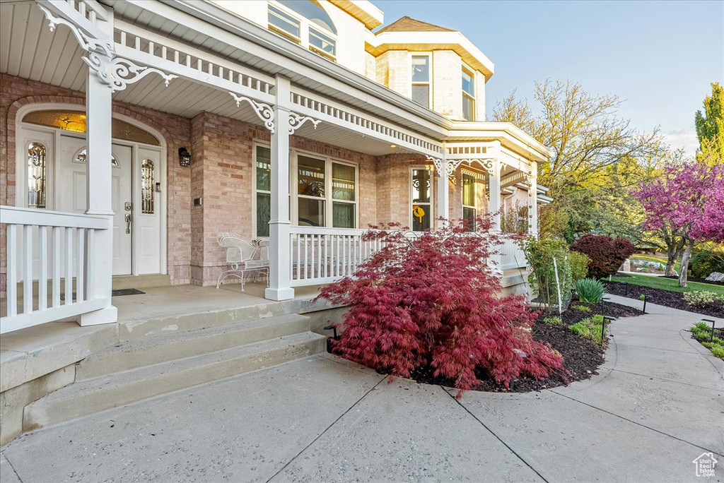 Doorway to property with covered porch and brick siding