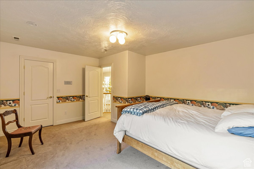 Bedroom featuring visible vents, a textured ceiling, baseboards, and light carpet