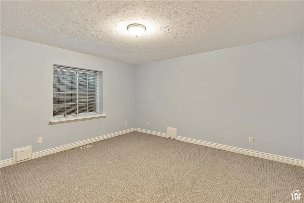Unfurnished room with baseboards, carpet, and a textured ceiling