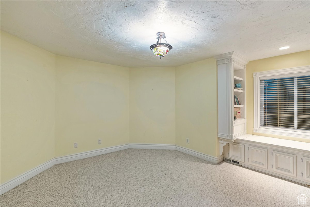 Unfurnished room featuring a textured ceiling, baseboards, light colored carpet, and visible vents