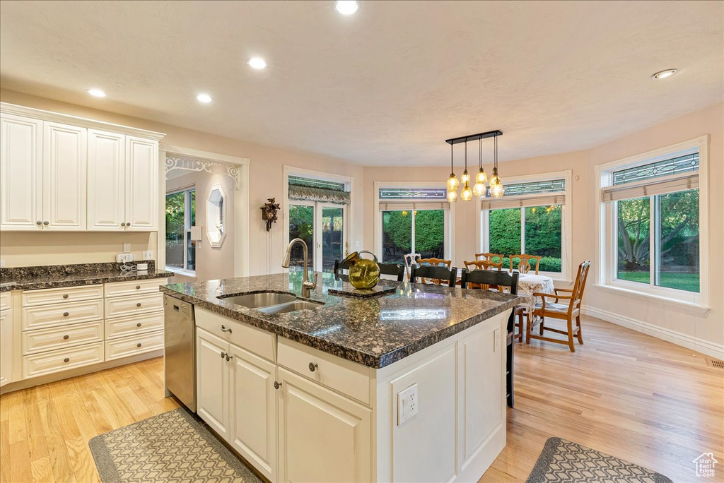 Kitchen with a sink, dishwasher, an island with sink, recessed lighting, and light wood-type flooring