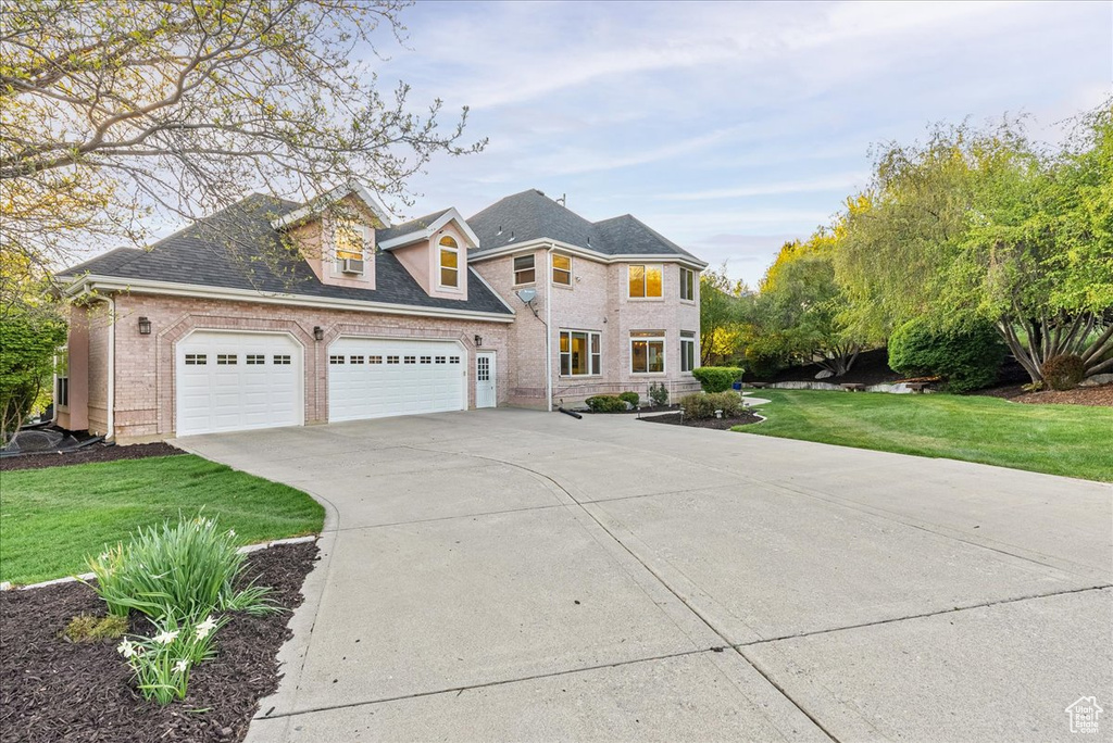 View of front facade with brick siding, a garage, a front yard, and concrete driveway