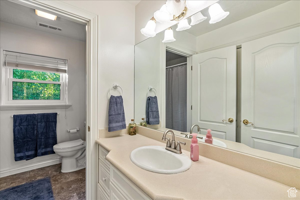 Bathroom with toilet, a shower with curtain, visible vents, and vanity