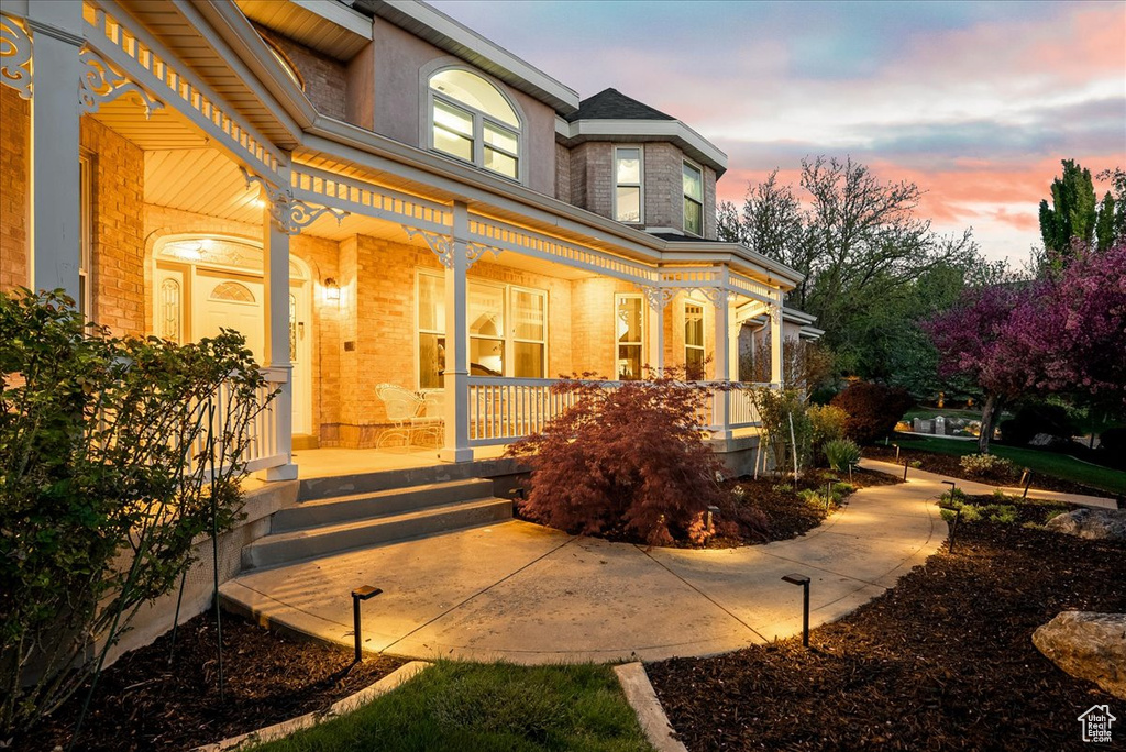 View of exterior entry featuring covered porch and brick siding
