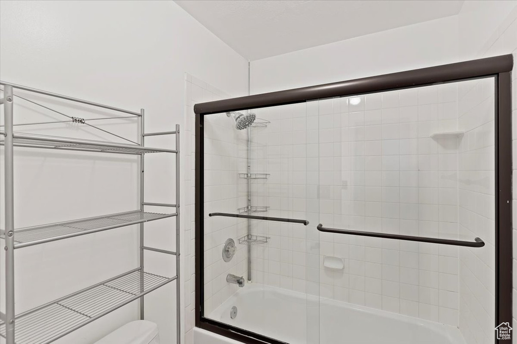 Full bathroom with shower / bath combination with glass door and toilet
