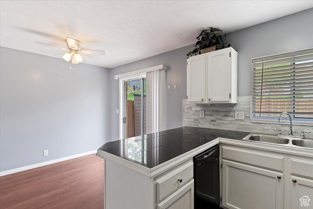 Kitchen featuring a sink, black dishwasher, a peninsula, a ceiling fan, and dark wood-type flooring