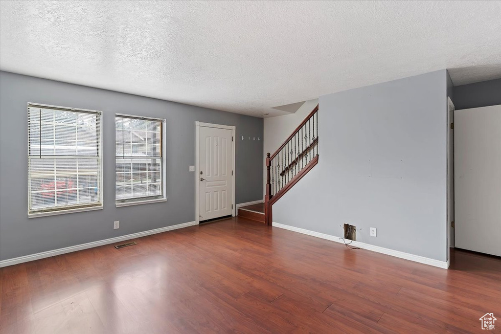 Entrance foyer featuring wood finished floors, a textured ceiling, stairs, and baseboards