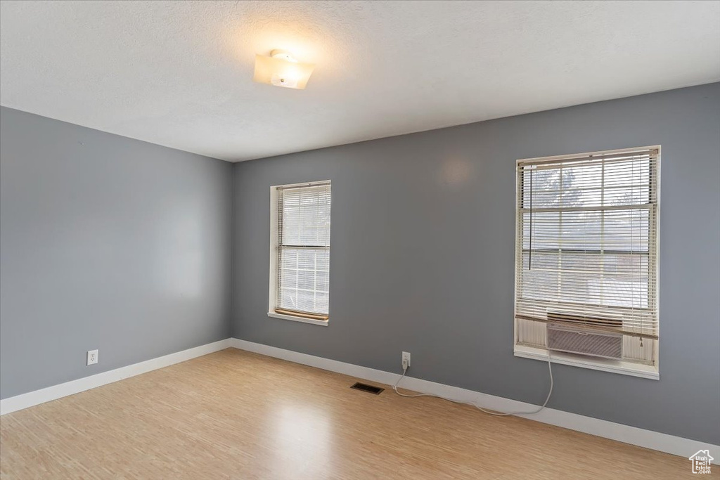 Unfurnished room featuring light wood-style floors, baseboards, and cooling unit