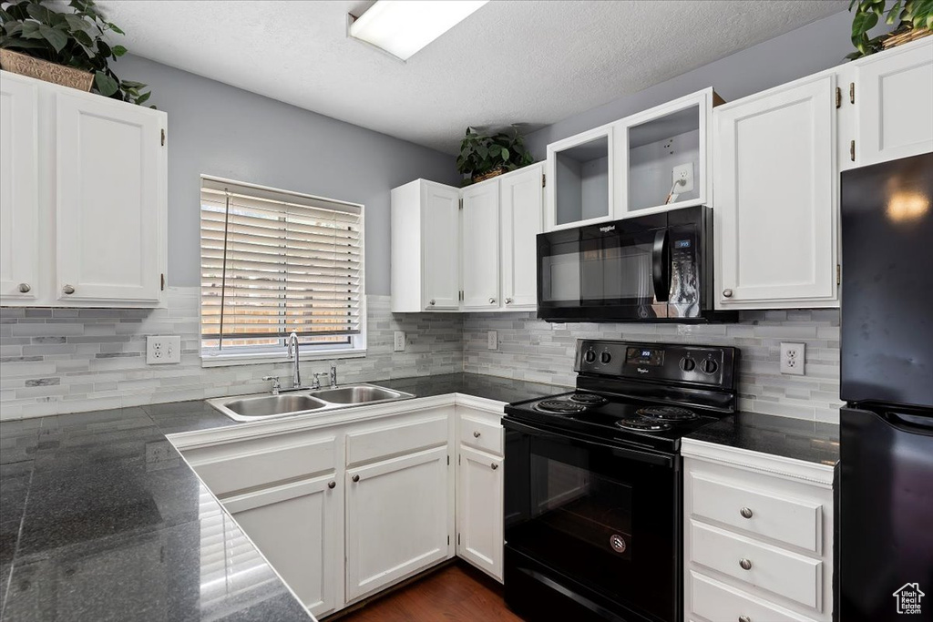 Kitchen with black appliances, a sink, white cabinetry, decorative backsplash, and a textured ceiling