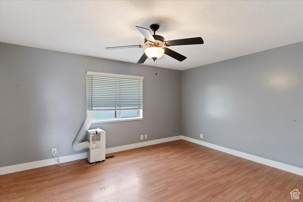 Unfurnished room with a ceiling fan, light wood-style flooring, and baseboards