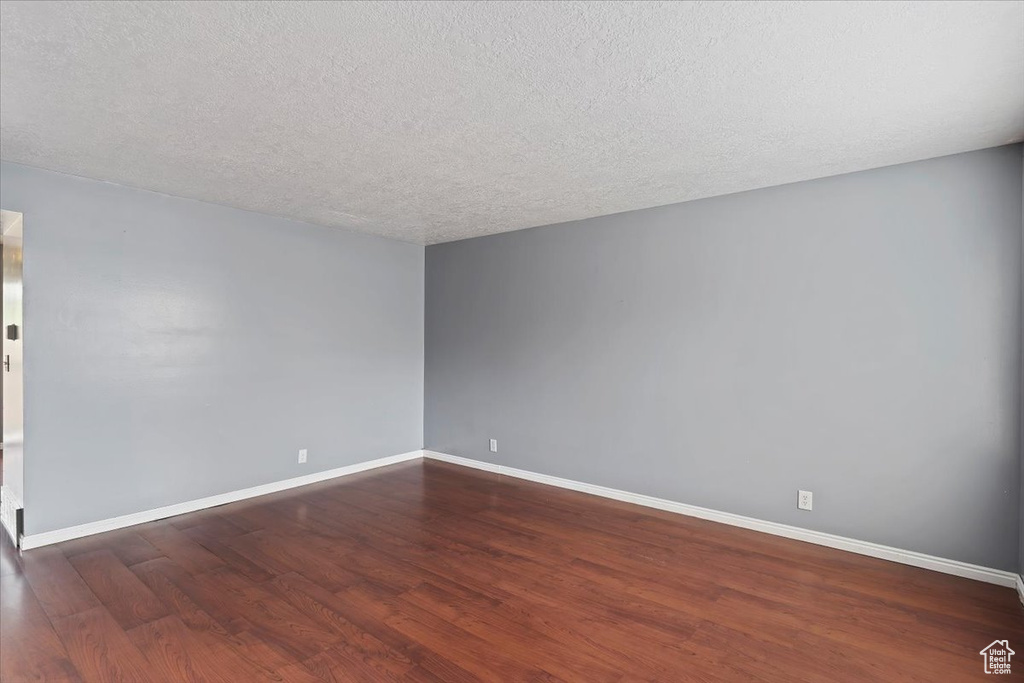 Spare room featuring wood finished floors, baseboards, and a textured ceiling