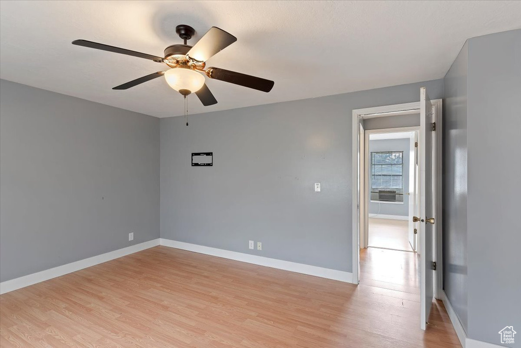Unfurnished room with light wood finished floors, ceiling fan, and baseboards
