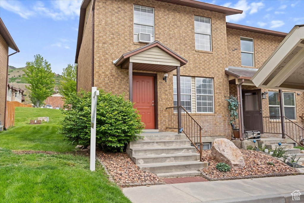 Townhome / multi-family property with a front lawn and brick siding