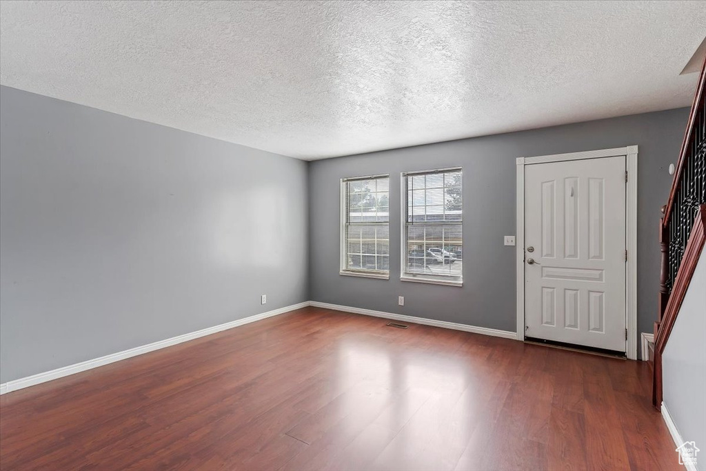 Entrance foyer with dark wood-style floors, a textured ceiling, and baseboards