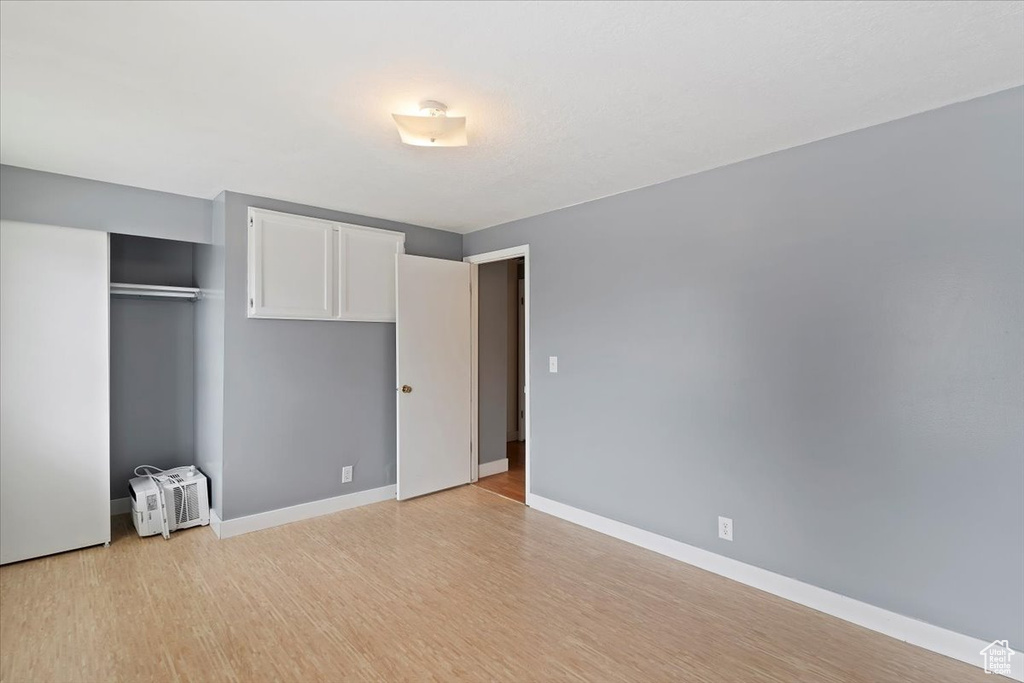 Unfurnished bedroom featuring light wood finished floors, a closet, and baseboards