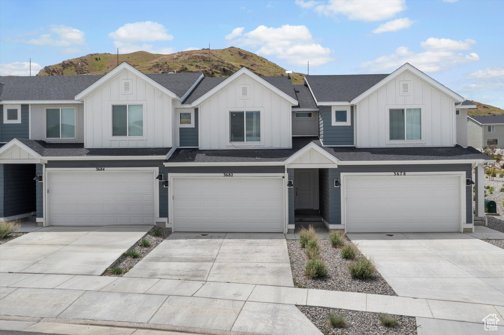 View of front facade with an attached garage, board and batten siding, a mountain view, and concrete driveway