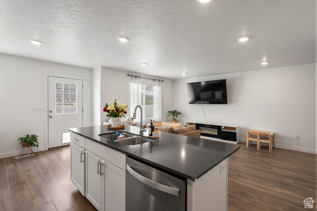 Kitchen featuring a sink, dishwasher, dark countertops, recessed lighting, and dark wood-type flooring