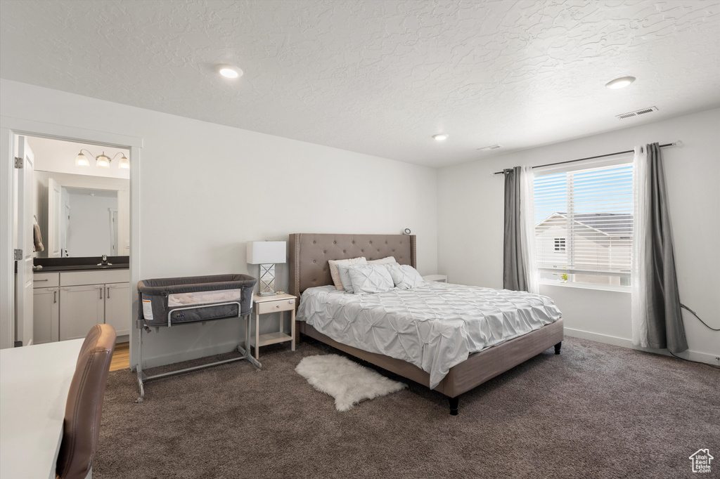Bedroom with a textured ceiling, carpet, ensuite bath, a sink, and recessed lighting