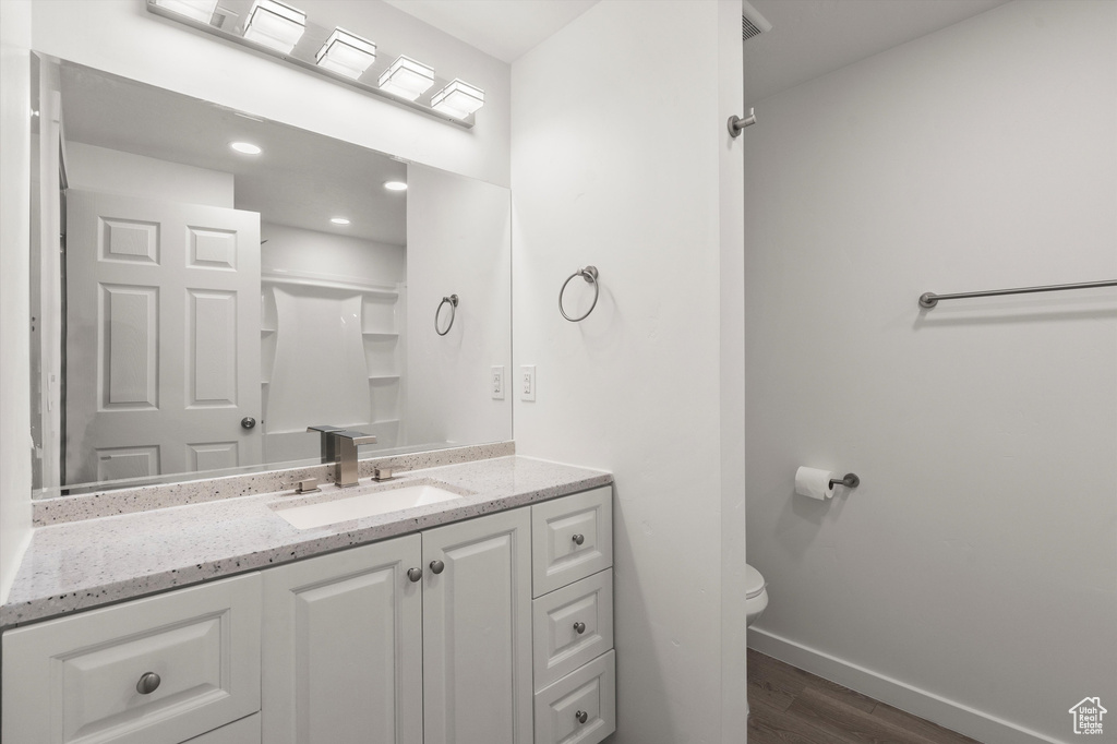 Bathroom with wood finished floors, baseboards, toilet, and vanity