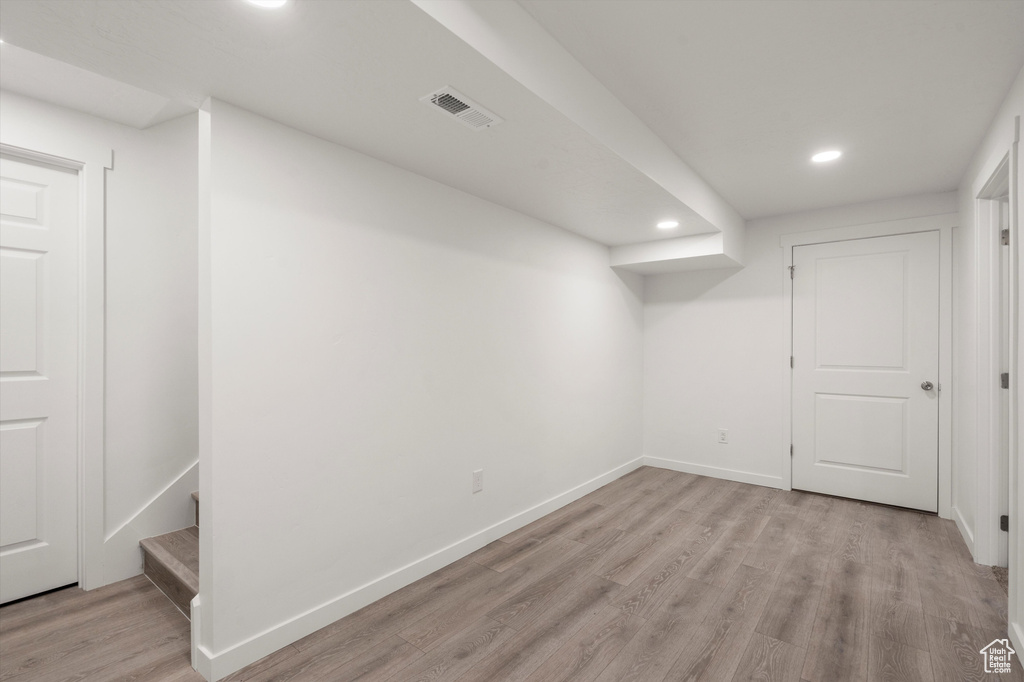Finished below grade area featuring recessed lighting, light wood-style floors, baseboards, and stairs
