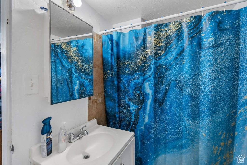 Bathroom with vanity, a textured ceiling, and a shower with shower curtain
