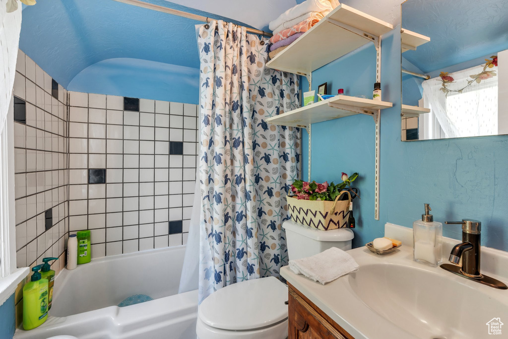 Bathroom featuring toilet, shower / bath combo with shower curtain, and vanity