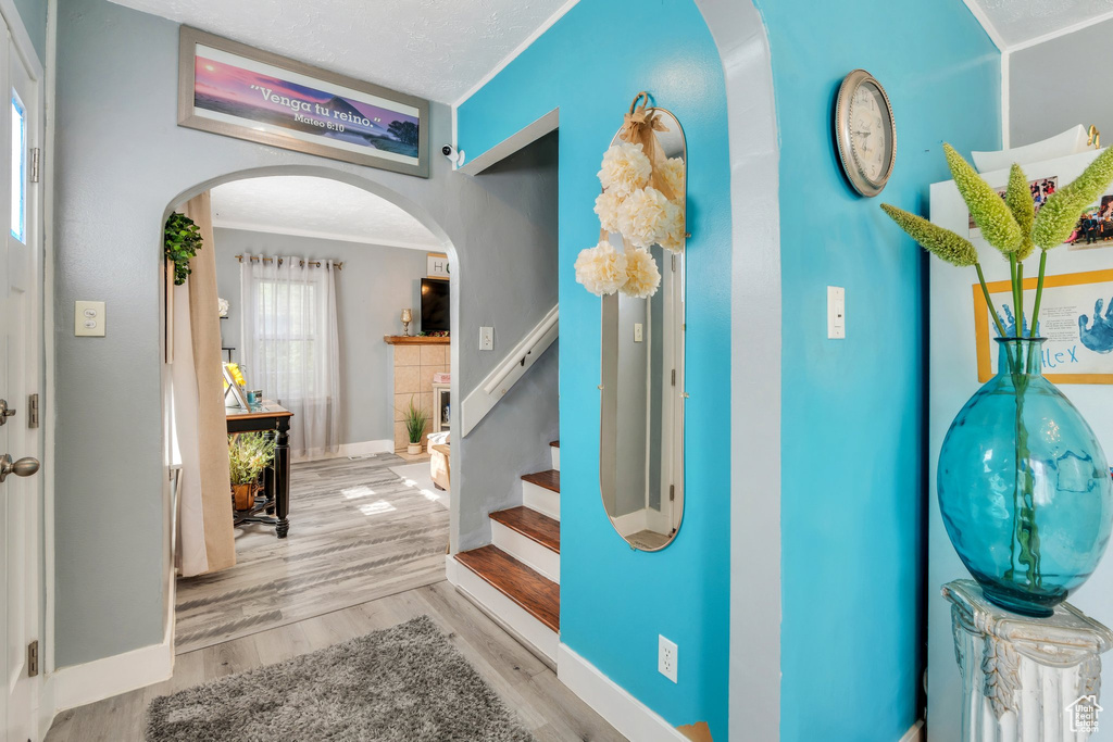 Entrance foyer featuring arched walkways, wood finished floors, crown molding, baseboards, and stairway