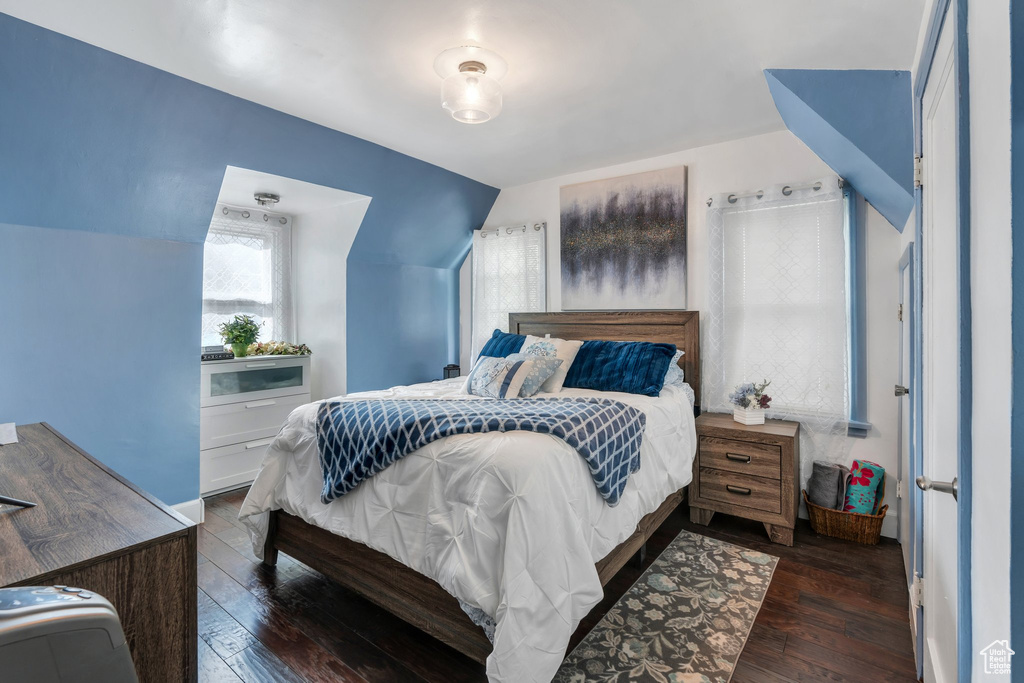 Bedroom with dark wood-style floors and lofted ceiling