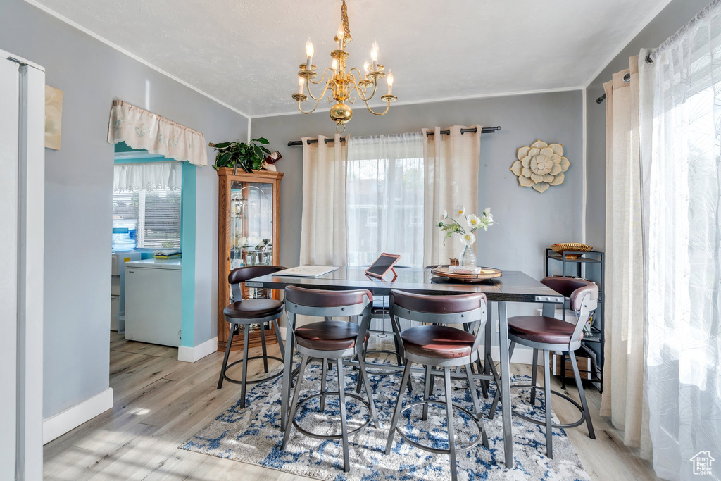 Dining space with a chandelier, ornamental molding, wood finished floors, and baseboards