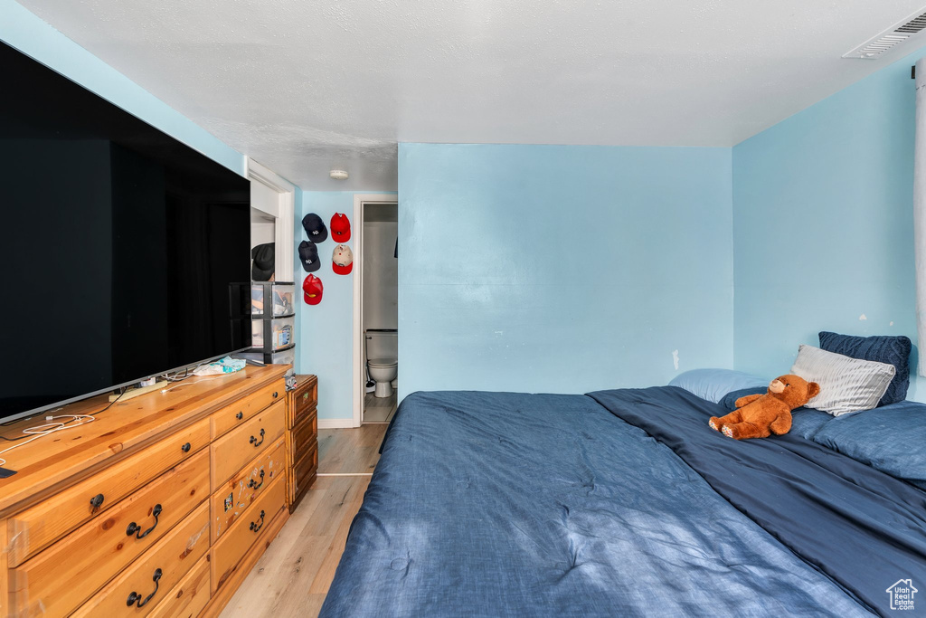 Bedroom featuring light wood-type flooring, ensuite bathroom, and baseboards