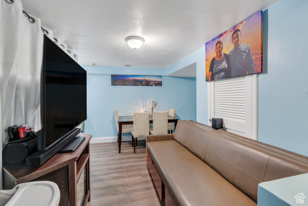 Living area with wood finished floors, a textured ceiling, and baseboards