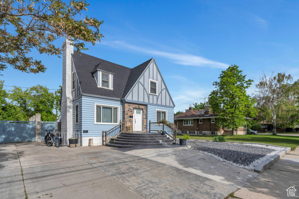 English style home with board and batten siding, a chimney, stone siding, and a shingled roof