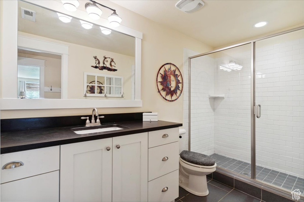 Full bathroom with a stall shower, toilet, tile patterned flooring, and vanity
