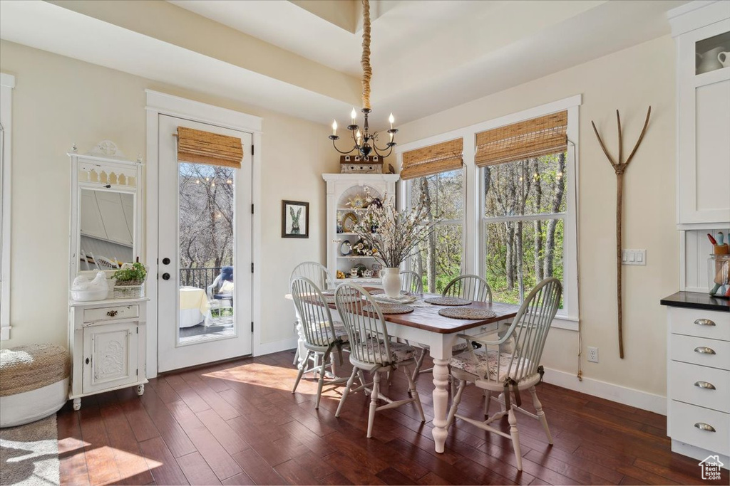 Dining space featuring a chandelier, dark wood finished floors, healthy amount of natural light, and baseboards