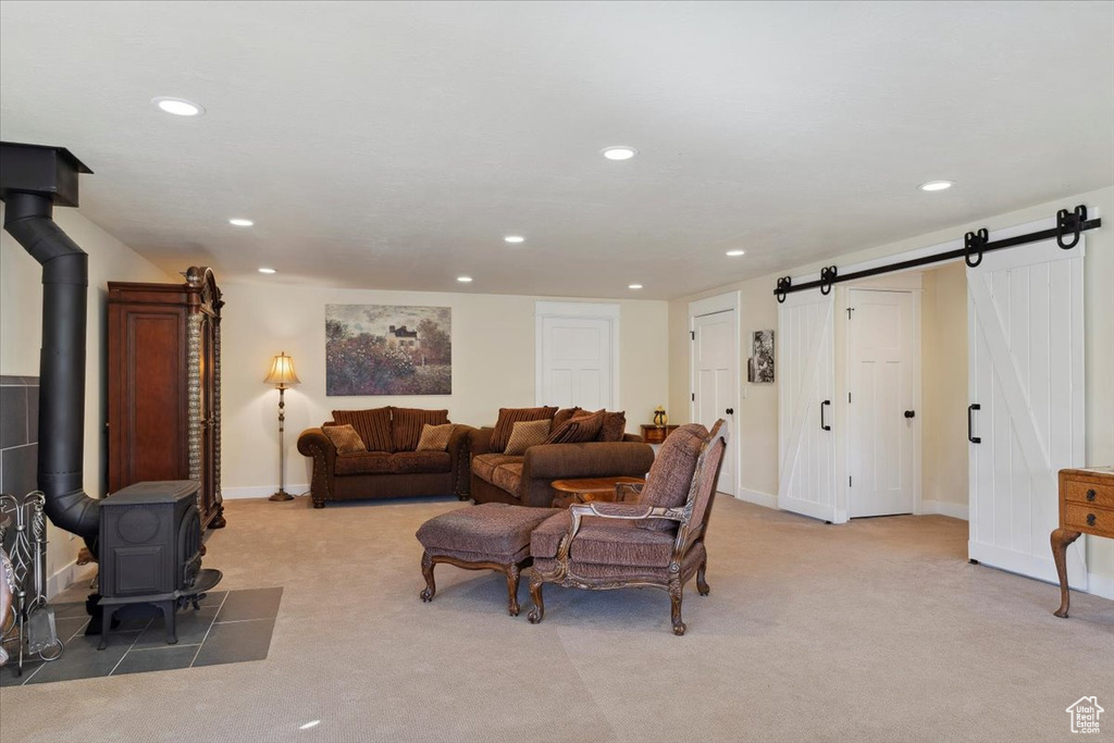Living area featuring a wood stove, light colored carpet, recessed lighting, a barn door, and baseboards